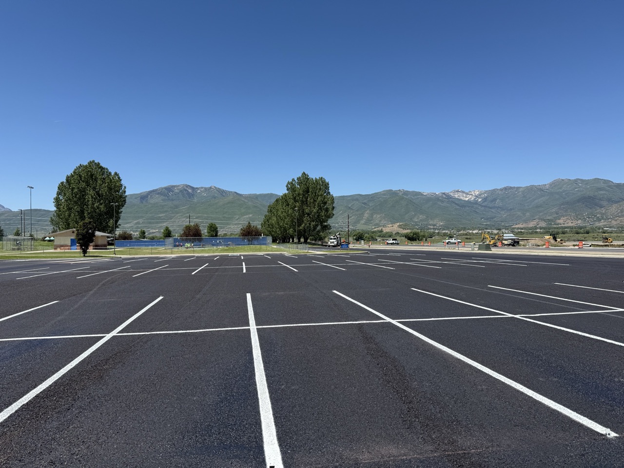 Wide newly striped parking lot with white stall lines and mountains behind it