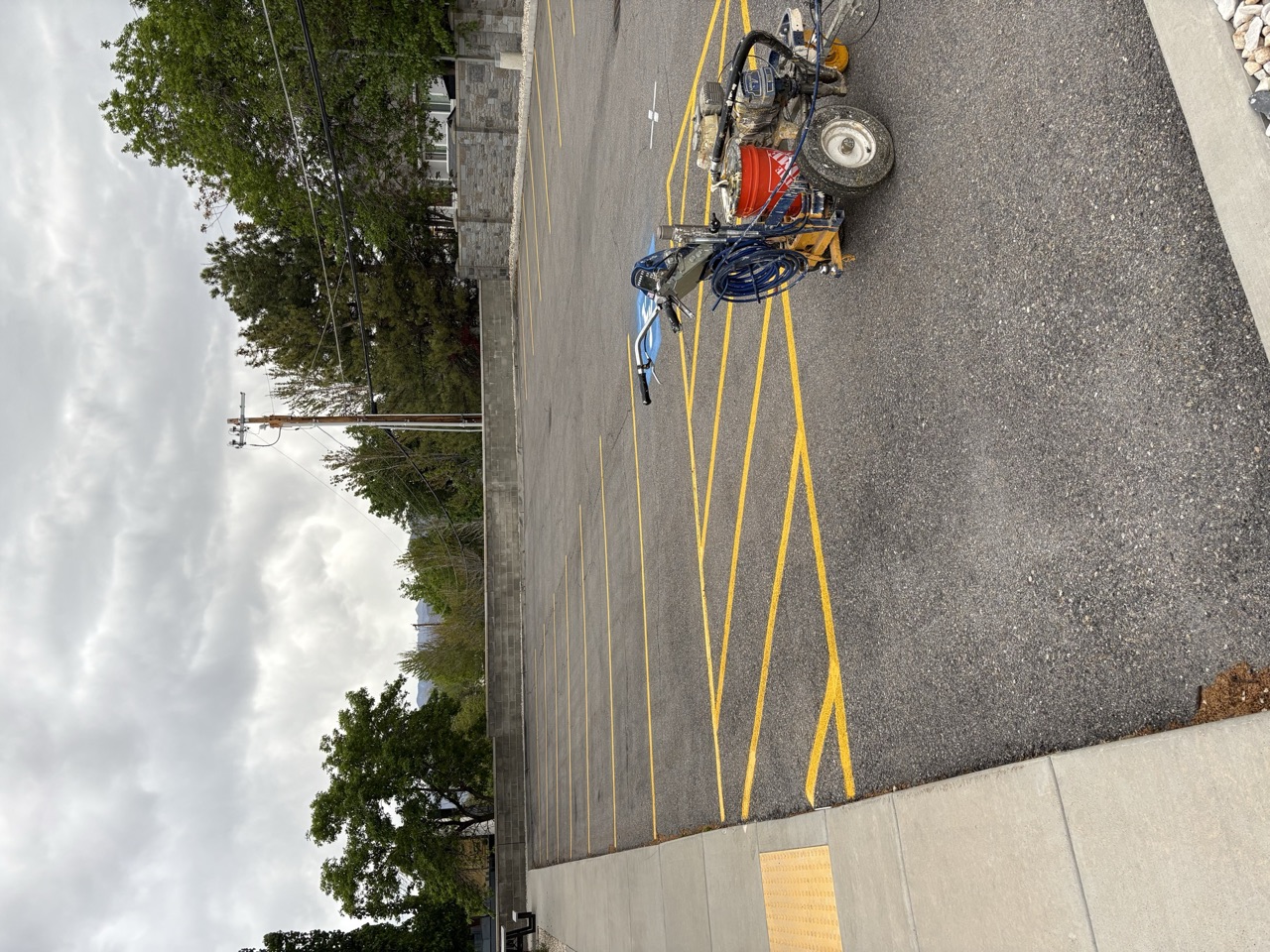 Fresh yellow access aisle beside striping equipment