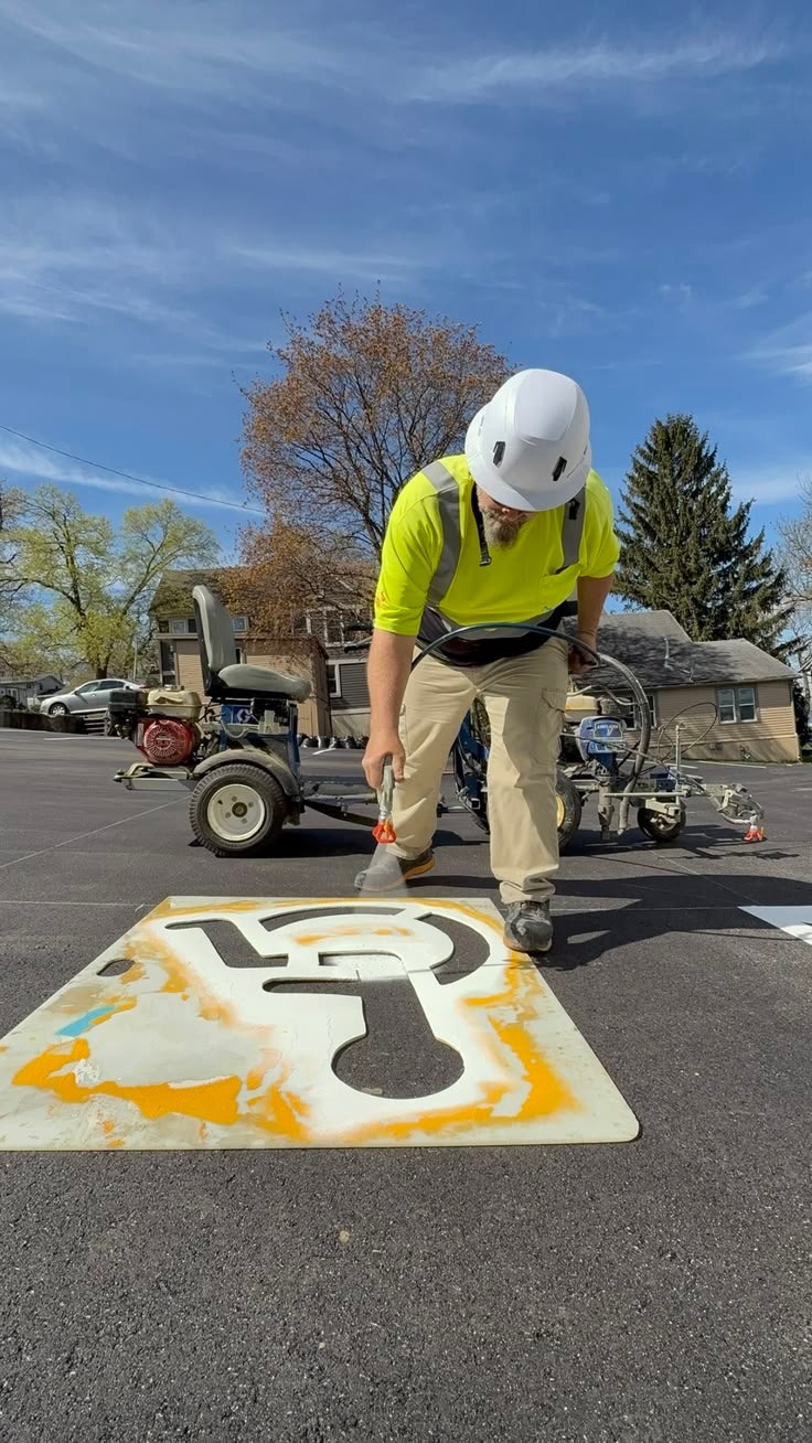 Premier Striping worker applying an accessible parking symbol with a stencil