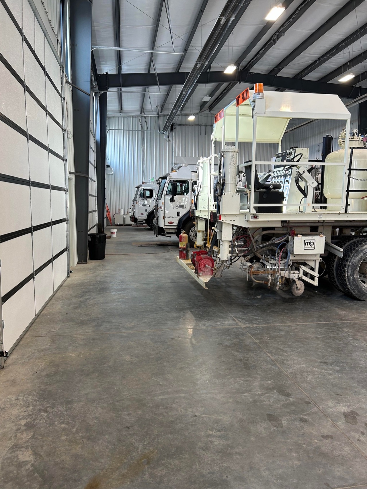Line-striping trucks and equipment parked inside the Premier Striping facility